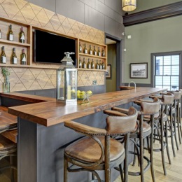 a bar with stools and a table with bottles on it